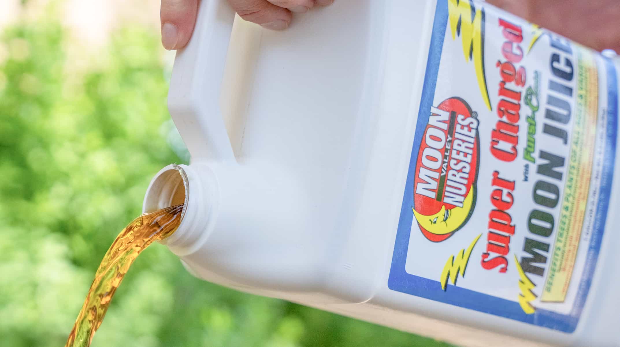 Moon Juice bottle being poured onto tree